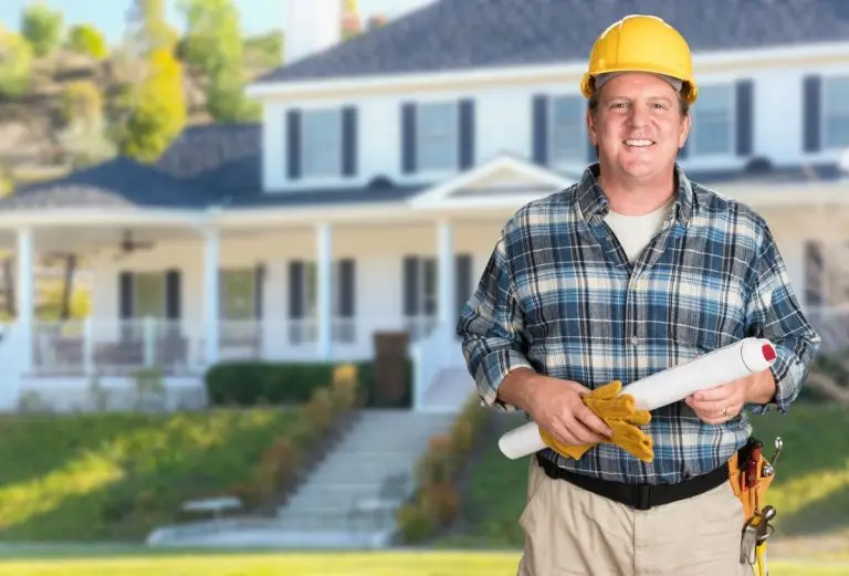 contractor with plans and hard hat in front of beautiful house