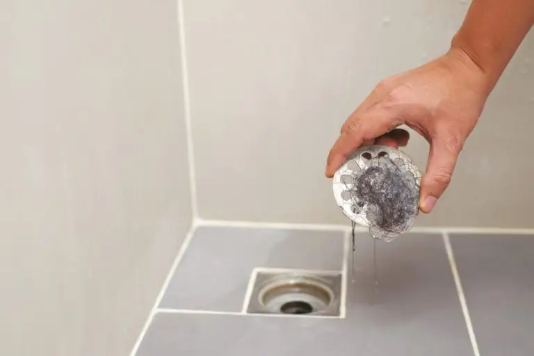 man holding drain cap with hair on it