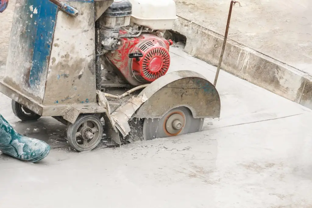 worker operating walk behind concrete saw